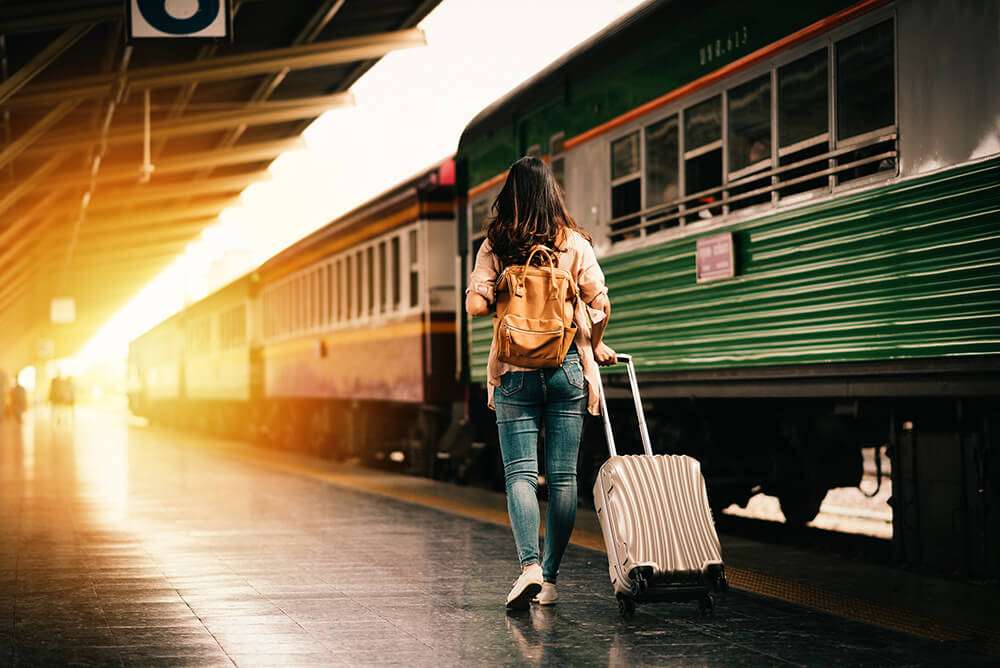 ผู้หญิงกำลังลากกระเป๋าขึ้นรถไฟ